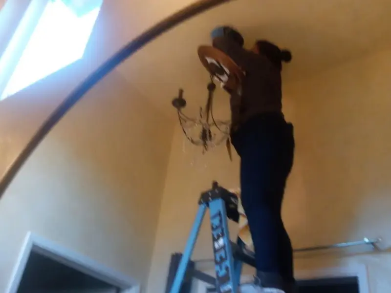 Electrician installing a chandelier in a Archer Lodge residence